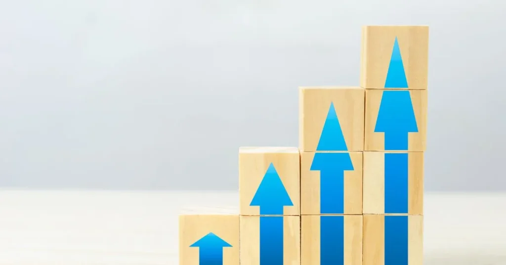 Gráfico-de-barras-doradas-con- flechas-azules-ascendentes-sobre- fondo-gris-claro-que- representa-crecimiento-y- rentabilidad-al-invertir-desde-el- extranjero.